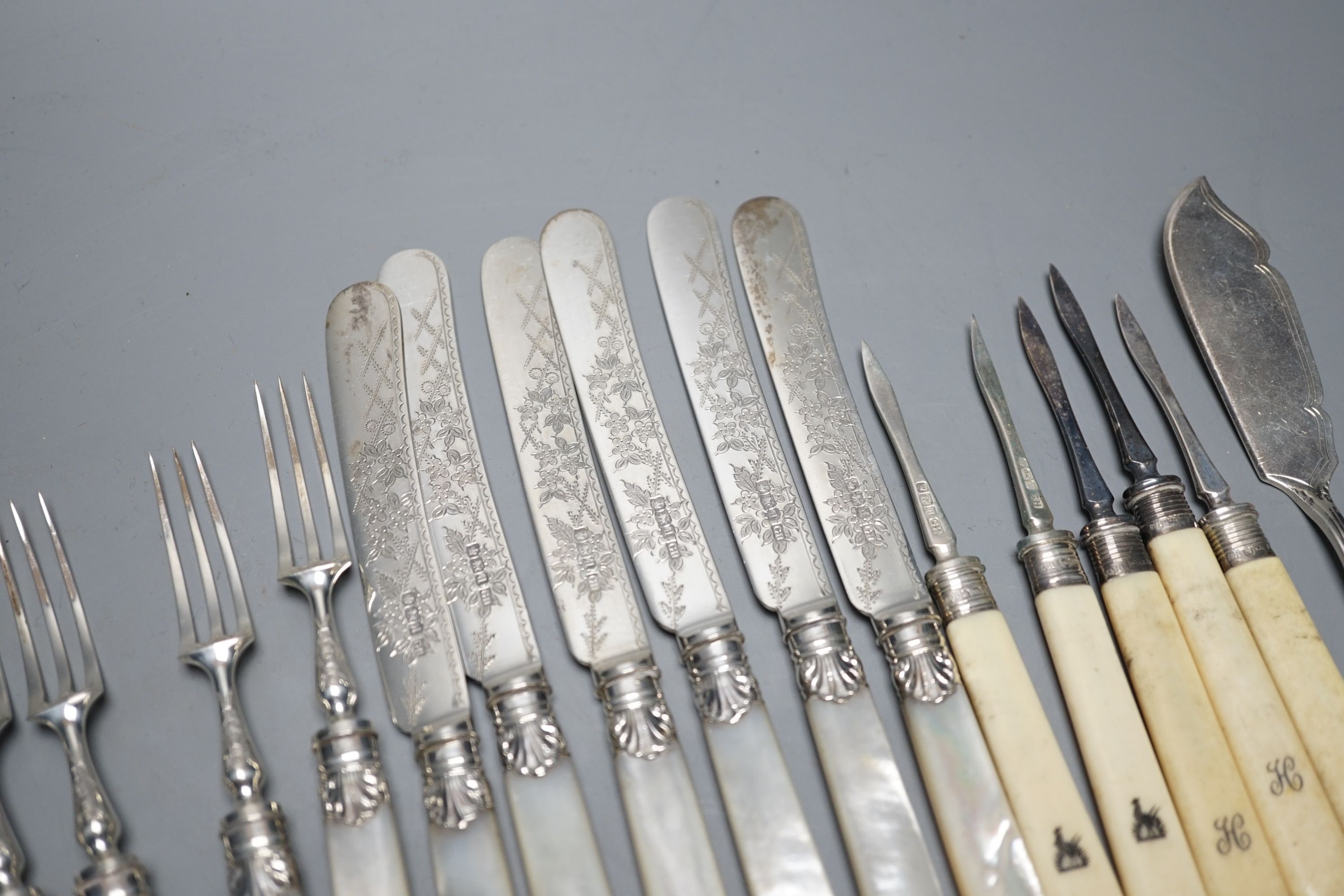 Six pairs of George V mother of pearl handled silver dessert eaters, George Howson, Sheffield, 1921, a pair of silver sugar tongs and assorted plated flatware.